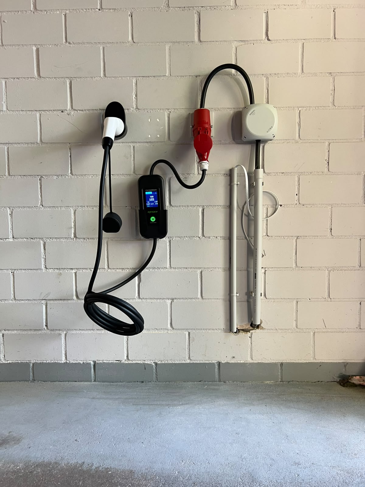 Installierte Wallbox mit Ladekabel an einer Hauswand